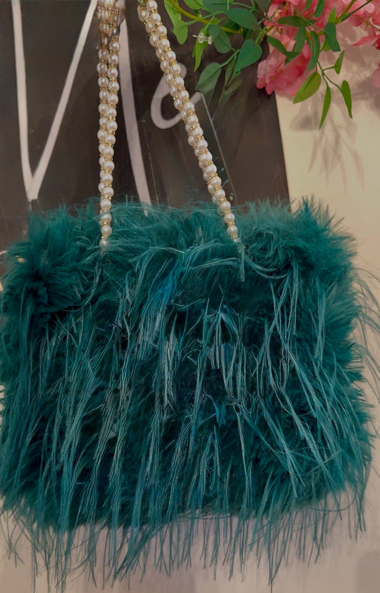 Teal feathered handbag with pearl strap on a blurred background